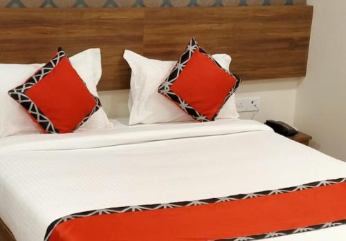 Una cama con dos almohadas rojas encima. en EMPIRE INN HOTEL, en Chennai