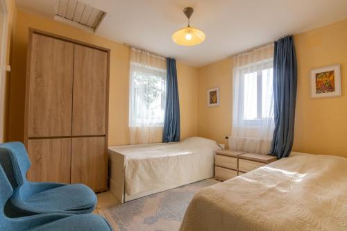 a bedroom with two beds and a blue chair at Kamala Kutir in Somogyvámos