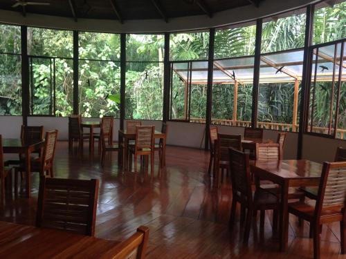 una sala da pranzo con tavoli, sedie e finestre di Pacoche Lodge a Pacoche