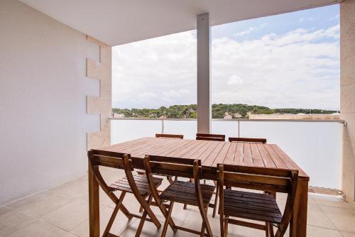 - une table et des chaises en bois dans une chambre avec une grande fenêtre dans l'établissement À 600m de la plage, bel appartement pour 6, à Lacanau