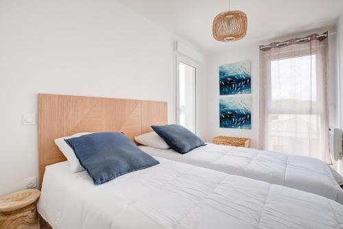 une chambre avec un grand lit blanc avec des oreillers bleus dans l'établissement À 600m de la plage, bel appartement pour 6, à Lacanau