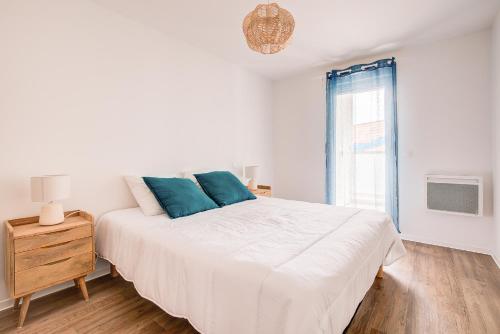 a white bedroom with a large bed and a window at Ressourcez vous dans ce bel appartement a Lacanau in Lacanau