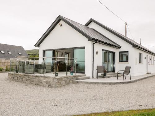 a white house with a patio and chairs in front of it at Traeannagh Bay House in Dungloe