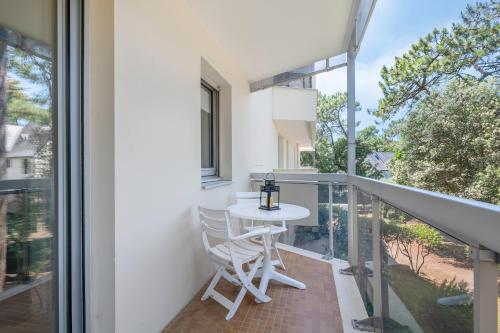 Elle comprend un balcon doté d'une table et de chaises blanches. dans l'établissement Appartement pour 4 avec balcon - centre-ville, à La Baule