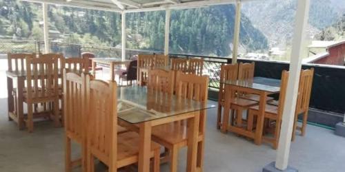 Midway Lodges Neelum Valley في Nīlam: غرفة طعام مع طاولة وكراسي خشبية