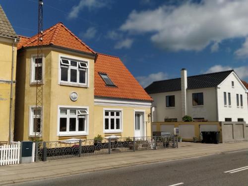 ein gelbes Haus mit orangefarbenem Dach auf einer Straße in der Unterkunft Fru Hald in Løkken