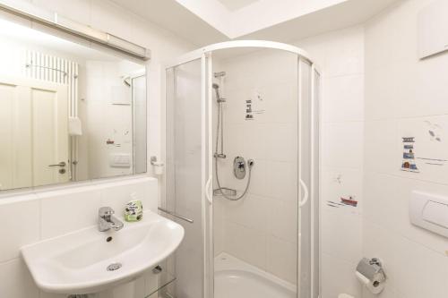 a white bathroom with a shower and a sink at Villa Strandperle Nr. 17 in Binz