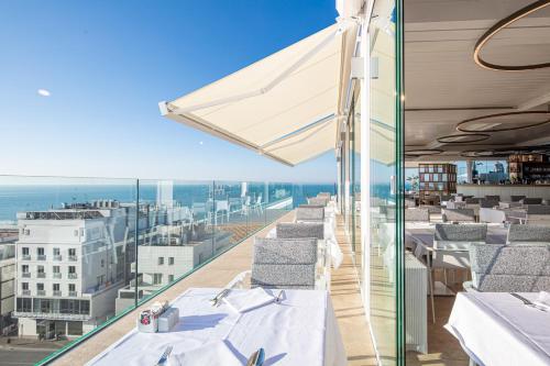 a balcony with tables and chairs and a view of the ocean at THE ONE CAORLE - Hotel & Apartments in Caorle