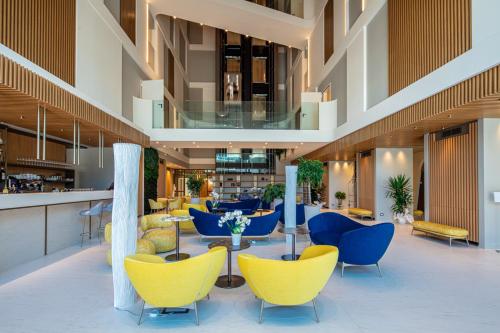 a lobby with blue and yellow chairs and tables at THE ONE CAORLE - Hotel & Apartments in Caorle