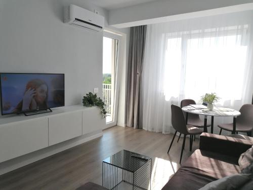 a white living room with a tv and a table at SunsetView Apartment in Oradea