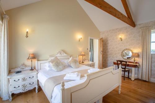 a bedroom with a large white bed and a desk at Ty Llo in Kidwelly
