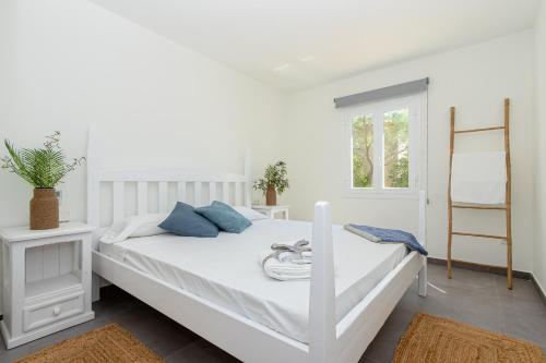 a white bedroom with a white bed with blue pillows at Apartment Jedy Balear By homevillas360 in Son Serra de Marina