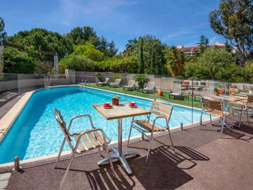 a table and chairs next to a swimming pool at ibis Hyeres Centre in Hyères