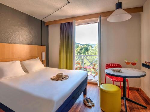 ibis Hyeres Centre في هييريس: غرفة فندقية بسرير وطاولة ونافذة