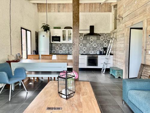 a living room with a table and a kitchen at La Belle Petite Ferme Rosiers de Julliac 19350 in Les Bos