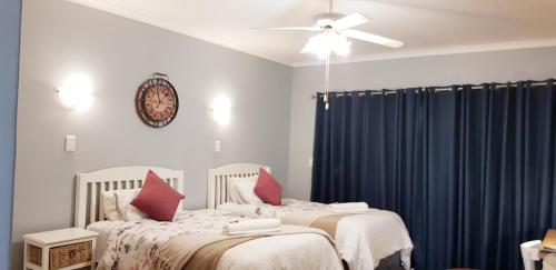 a bedroom with two beds and a ceiling fan at Graceland Guesthouse in Potchefstroom