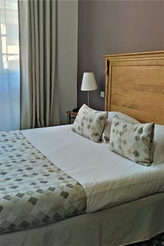 a bedroom with a large bed with a wooden headboard and pillows at Hostellerie du Val d'Or in Mercurey