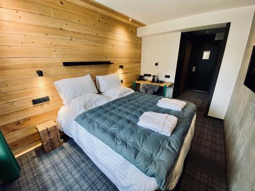 a large bed in a room with a wooden wall at Hôtel 16 | 150 Montagne & Spa Nuxe in Vars