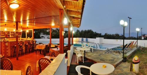 Un patio con mesas y sillas y una piscina. en Primavera Paradise Apartments, en Agios Nikolaos