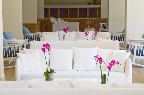 eine weiße Couch mit weißen Kissen und lila Blumen in der Unterkunft Sandy Beach Hotel & Spa - ex Sentido in Larnaka