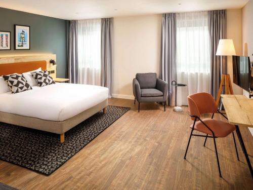 a hotel room with a bed and a chair at Aparthotel Adagio London Sutton Point in Sutton