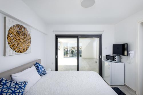 a white bedroom with a bed and a tv at Solaar Apartments st Lazarous in Larnaca