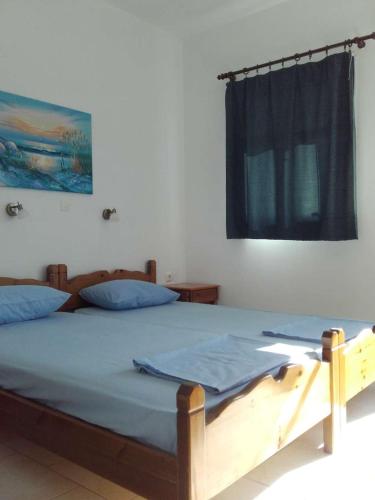 um quarto com uma cama com lençóis azuis e uma janela em Nikos Taverna and Apartments em Lefkos Karpathou