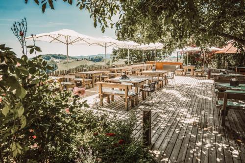a restaurant with wooden tables and white umbrellas at Weinhotel Maitz Wolfgang in Ratsch an der Weinstraße