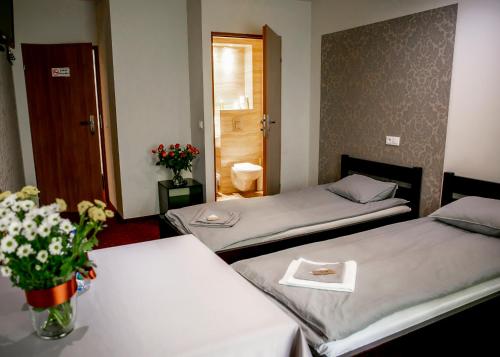 dwa łóżka w pokoju z kwiatami na stołach w obiekcie Kamionki w mieście Sosnowiec