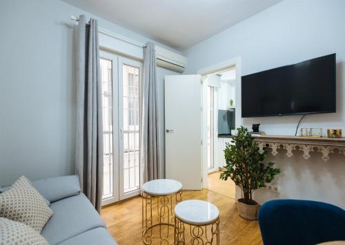 een woonkamer met een blauwe bank en een tv bij Feijóo Suite Apartment in Sevilla