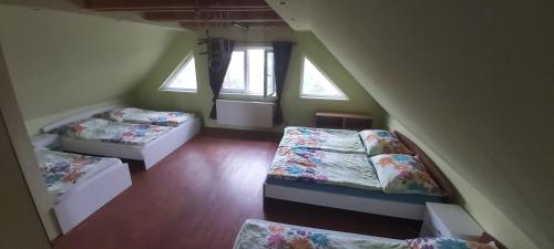 a attic room with three beds and two windows at Chata u rybníka in Mšecké Žehrovice