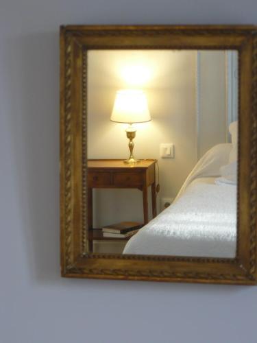 a mirror with a lamp on a table next to a bed at La Maison de Saumur in Saumur