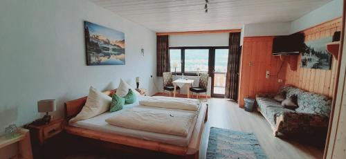 ein Schlafzimmer mit einem Bett und einem Sofa in einem Zimmer in der Unterkunft Alpenappartements Schwalbennestl in Mittenwald