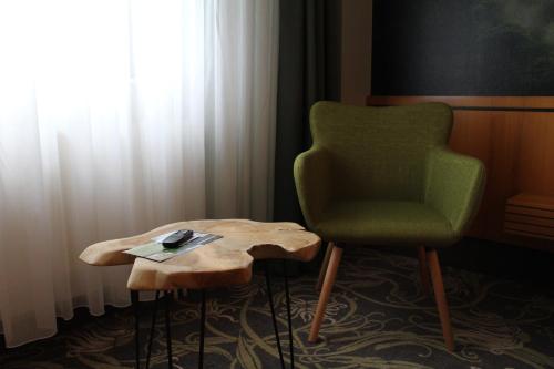 a green chair and a table in a room at Hotel Rennsteig in Masserberg