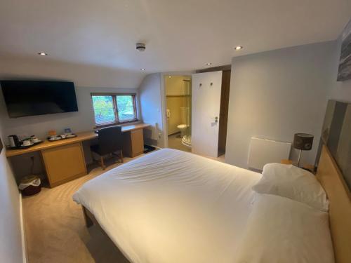 a bedroom with a white bed and a desk and a computer at The King and Queen in West Malling