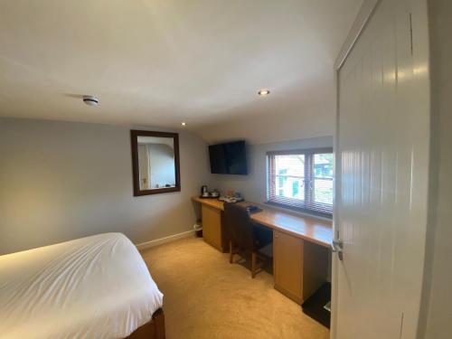 a bedroom with a bed and a desk and a window at The King and Queen in West Malling