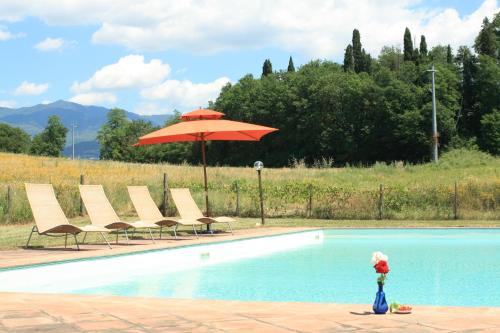 een zwembad met een rode parasol en stoelen en een tafel en parasol bij Agriturismo Torre del Castellano in Rota