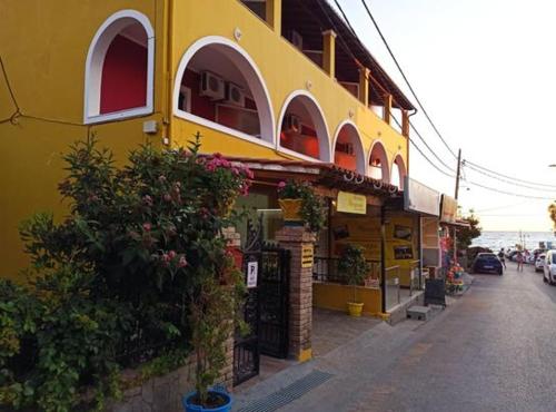 a yellow building on the side of a street at MARGARITAS' ROOMS in Agios Gordios