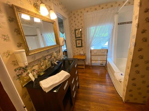ein Badezimmer mit einem Waschbecken, einem Spiegel und einer Badewanne in der Unterkunft Bernard Gray Hall Bed and Breakfast in Niagara on the Lake