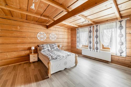ein Schlafzimmer mit Holzwänden und ein Bett in einem Zimmer in der Unterkunft Domek u Stochów in Biały Dunajec