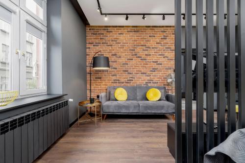 a living room with a couch against a brick wall at Old Town Studio Good Vibes by Renters in Krakow