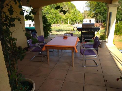 un patio con mesa, sillas y piano en Villa Les Marmottes, en Le Luc