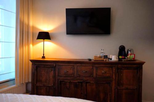 1 dormitorio con tocador de madera y TV en la pared en Kirisavan Bed&Breakfast, en Borgloon