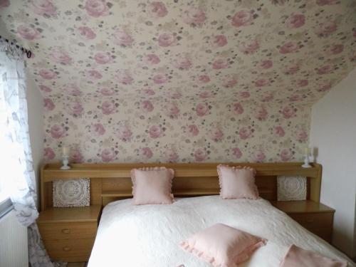 ein Schlafzimmer mit einem Bett mit rosa Blumen an der Wand in der Unterkunft Rosentraum in Hain