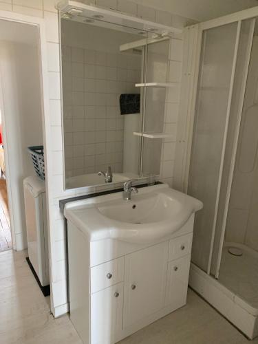 une salle de bain blanche avec un lavabo et un miroir dans l'établissement Les Jardins d'Élise, calme et verdure à Lure, à Lure