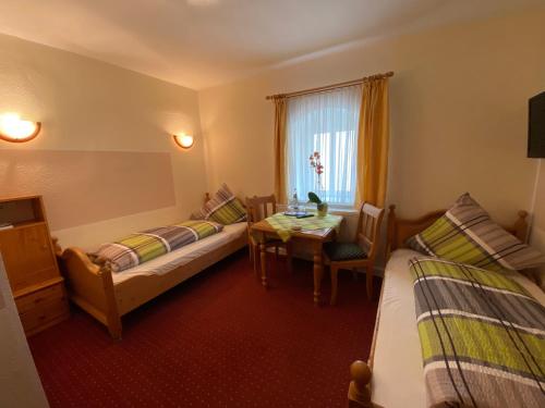 a room with two beds and a table and a window at Kastanienhof in Müglitztal