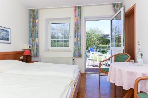 1 dormitorio con 2 camas, mesa y sillas en Hotel-Pension Störtebeker, en Bensersiel