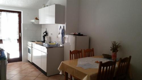 a kitchen with a table and a white refrigerator at Apartmani Ana Schon in Cres