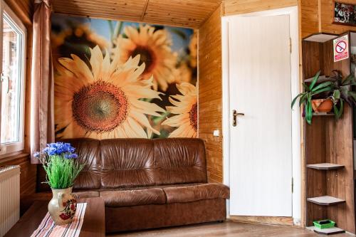 a brown leather couch in a room with a flower mural at Bilya Richky Hotel in Kamianets-Podilskyi
