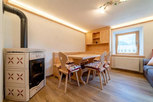 cocina con mesa, fogones y sillas en Ospitalità Diffusa Laste Dolomites Cèsa del Bèrba Jaco, en Rocca Pietore